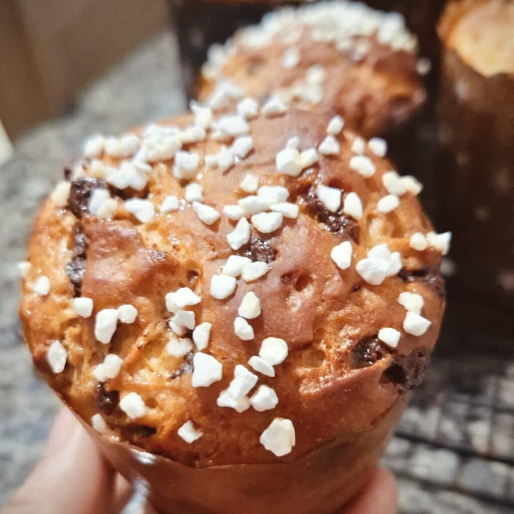 Panetone sem glúten com granulado branco, segurado na mão por aluna